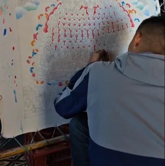 Himalayan master artist painting a traditional thangka with mineral pigments on cotton canvas